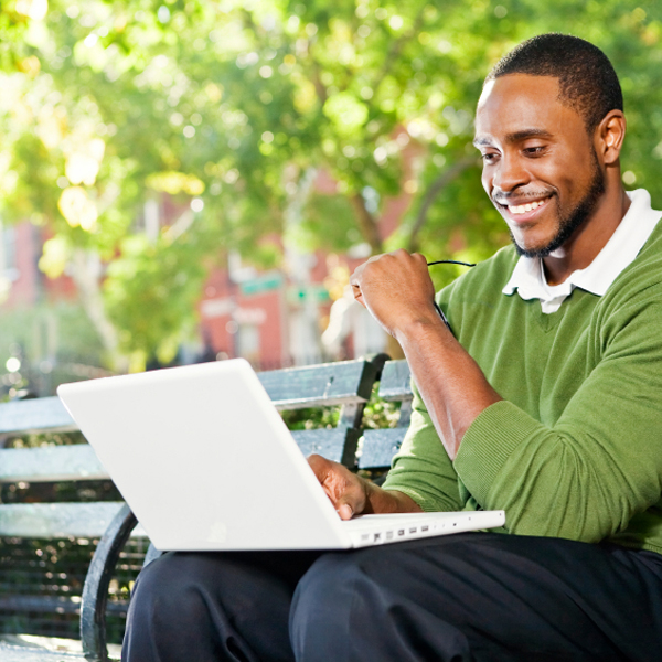 Man doing traffic school at a park on laptop